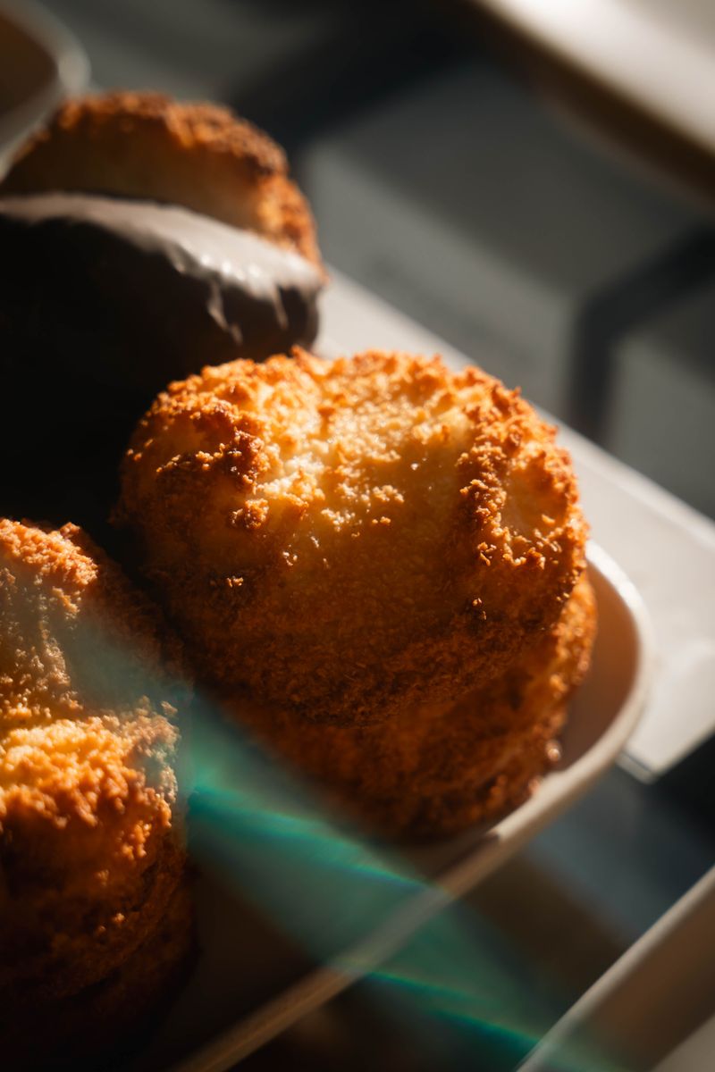 Delicious golden coconut pastries stacked in warm sunlit display, tempting and fresh.