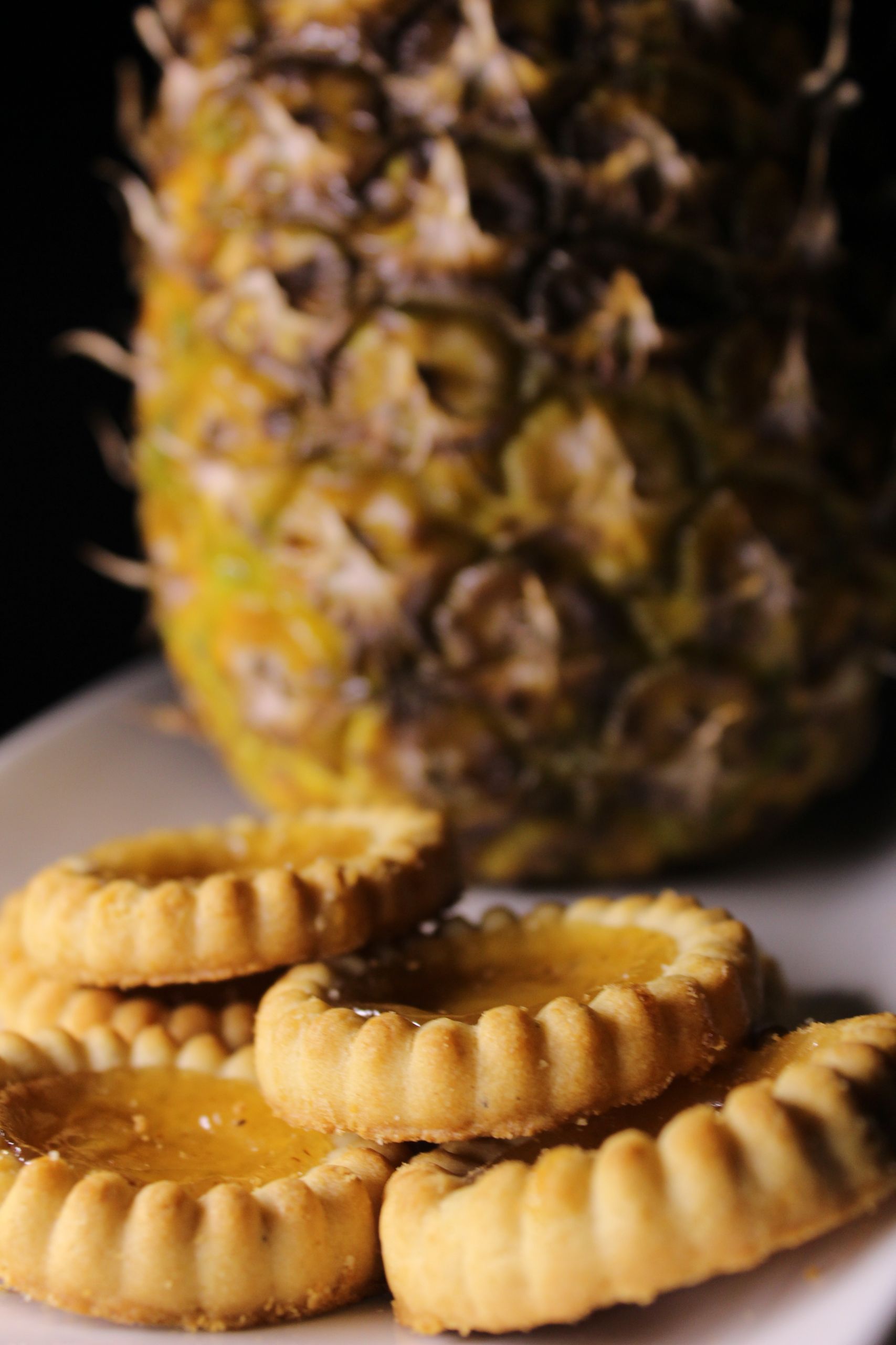 Delicious pineapple jam filled biscuits with a fresh pineapple in the background.