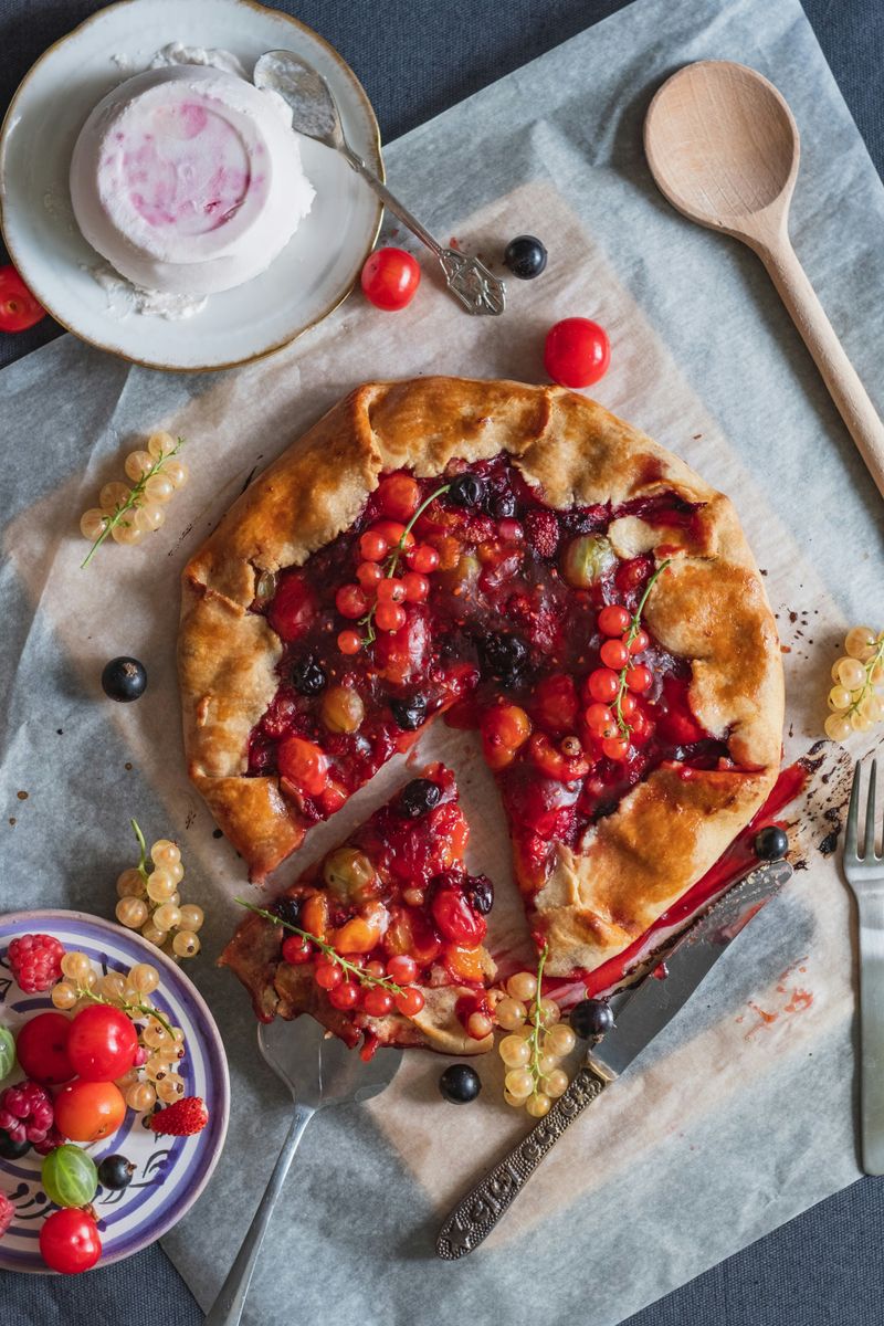 Delicious rustic mixed berry galette with currants and raspberries on parchment paper.