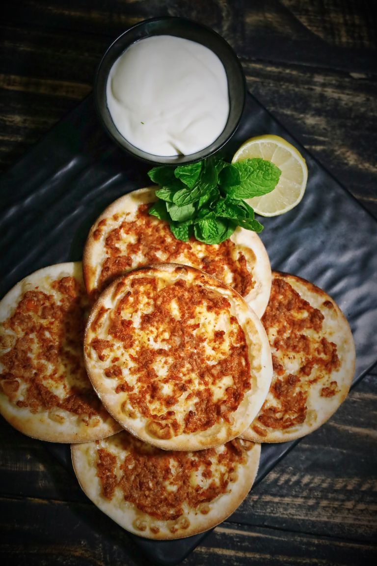 Delicious spiced minced meat flatbreads with yoghurt, mint, and lemon garnish. Perfect for a healthy meal.