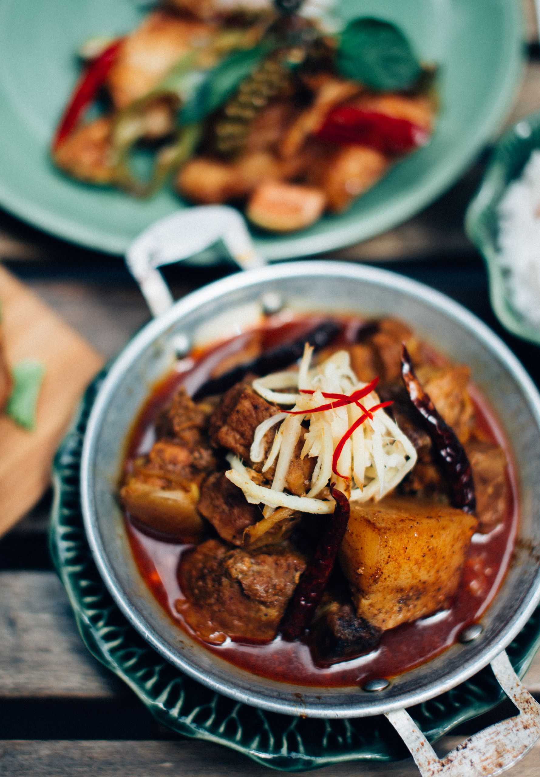 Delicious spicy beef stew with potatoes and garnished spices in a rustic setting, perfect for food enthusiasts.