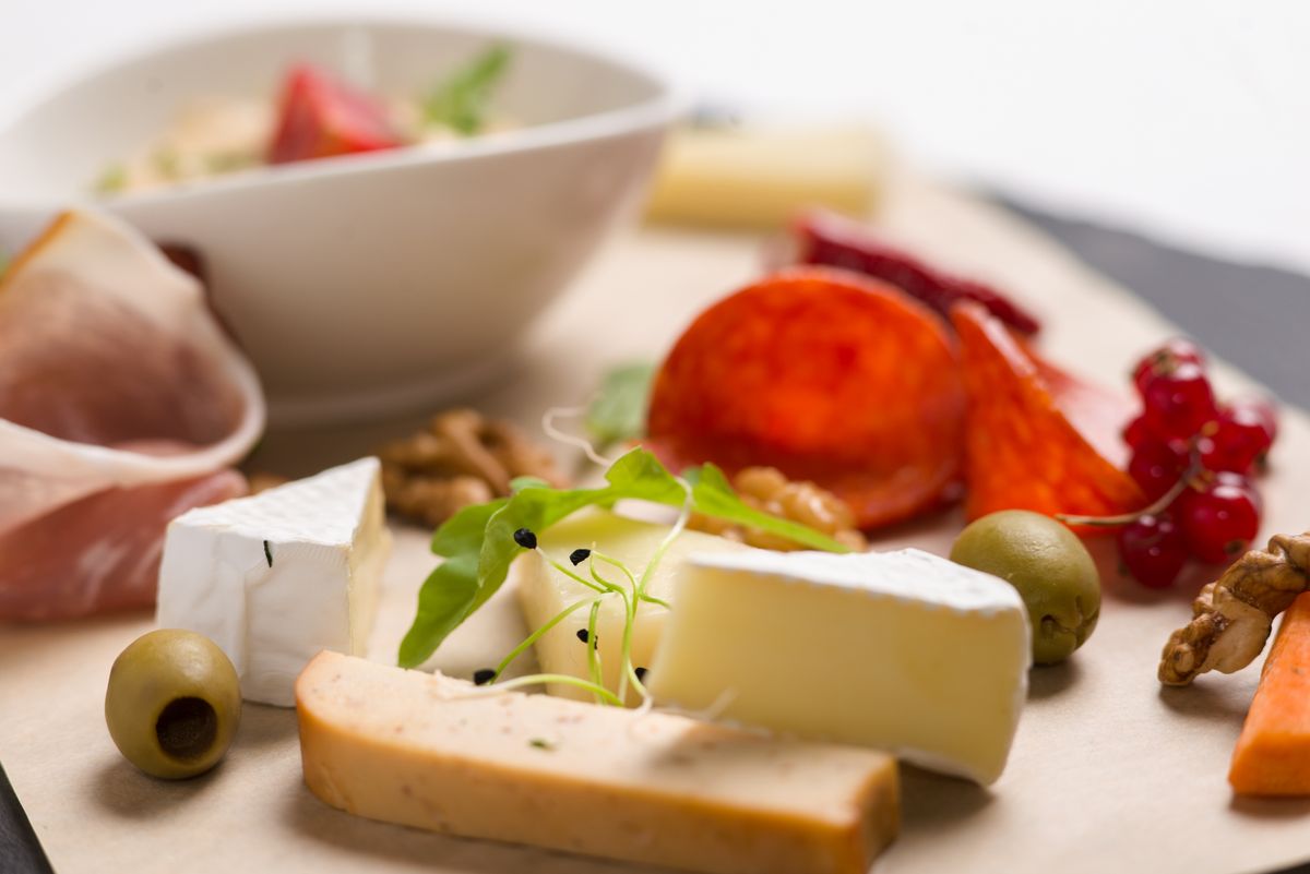Elegant cheese platter featuring assorted cheeses, meats, olives, and walnuts.