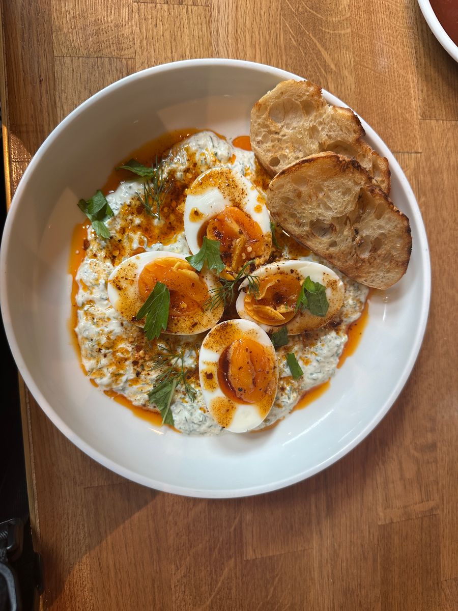 Enjoy a savory Thai breakfast featuring soft-boiled eggs and crispy bread in a vibrant setting.