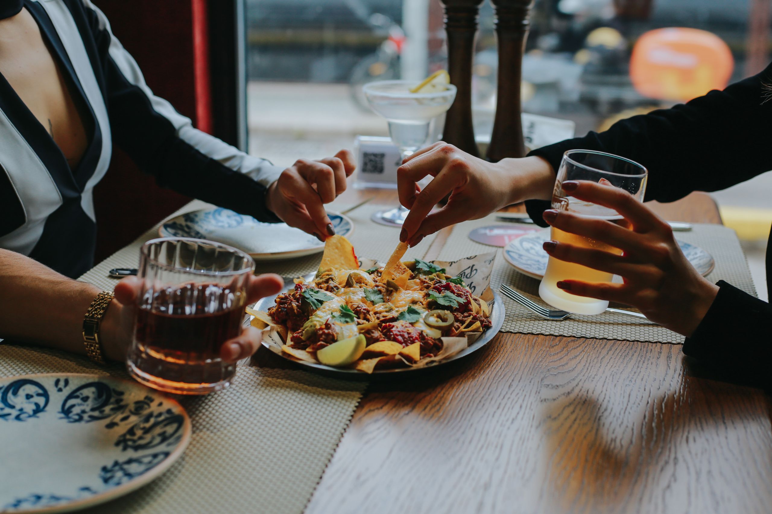 Friends enjoying drinks and nachos together in a relaxed restaurant setting.