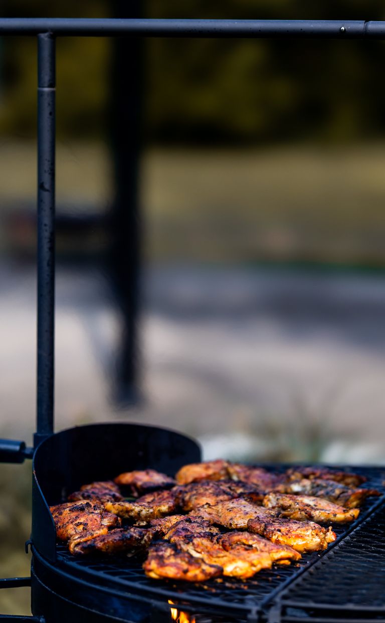Juicy marinated chicken pieces sizzling on an outdoor barbecue grill.