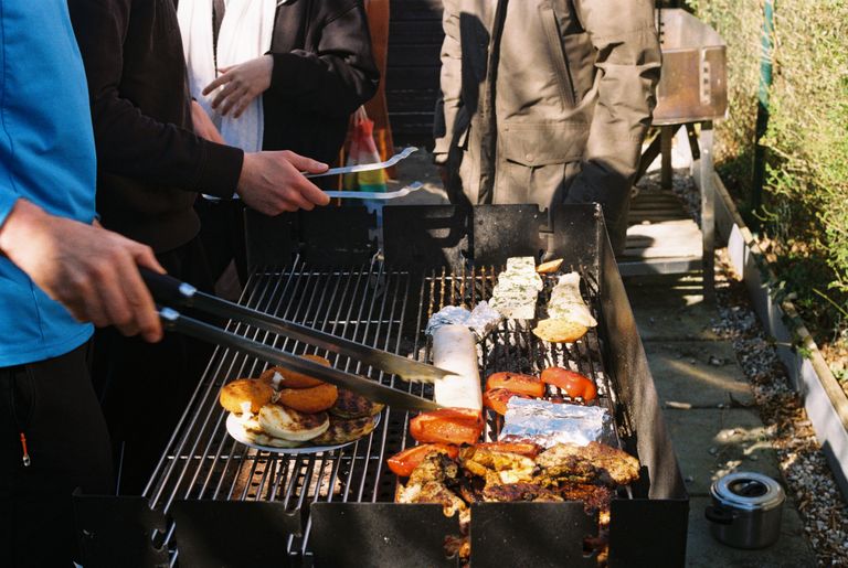 Men grilling assorted food at an outdoor barbecue event in Munich, Bavaria, Germany.