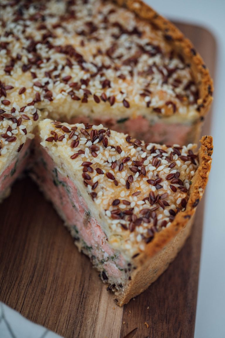 Mouthwatering baked salmon pie made at home, topped with crunchy seeds, beautifully sliced.