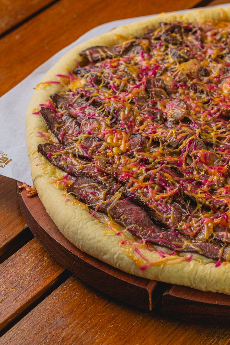 Mouthwatering beef and cheese pizza with vibrant toppings served on a wooden table.