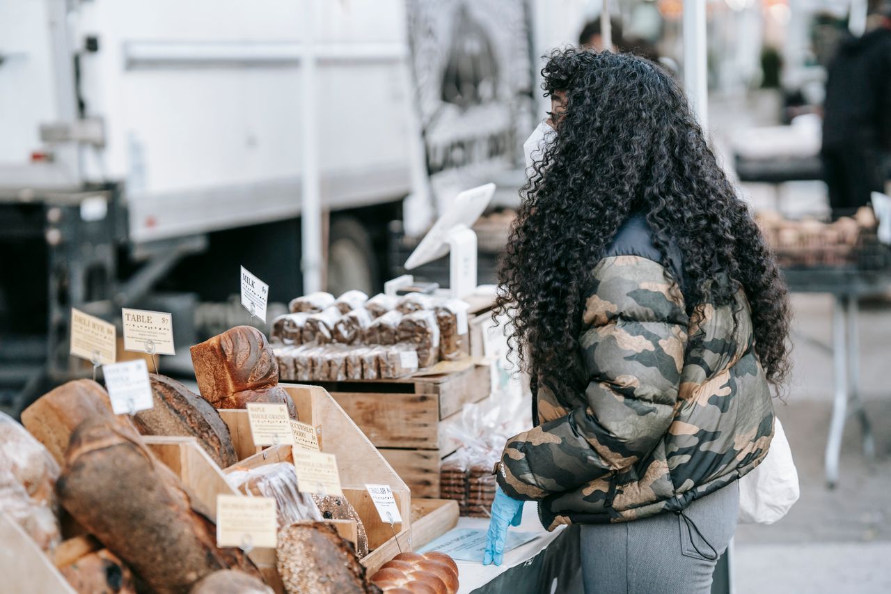 ethnic-woman-buying-bread-in-street-market