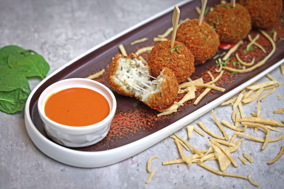 Satisfying crispy arancini served with a spicy red pepper dip on a stylish platter.