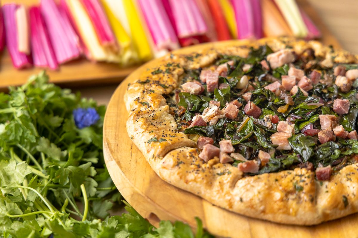 Savor a rustic galette topped with collard greens and diced ham. Perfect for a hearty meal.