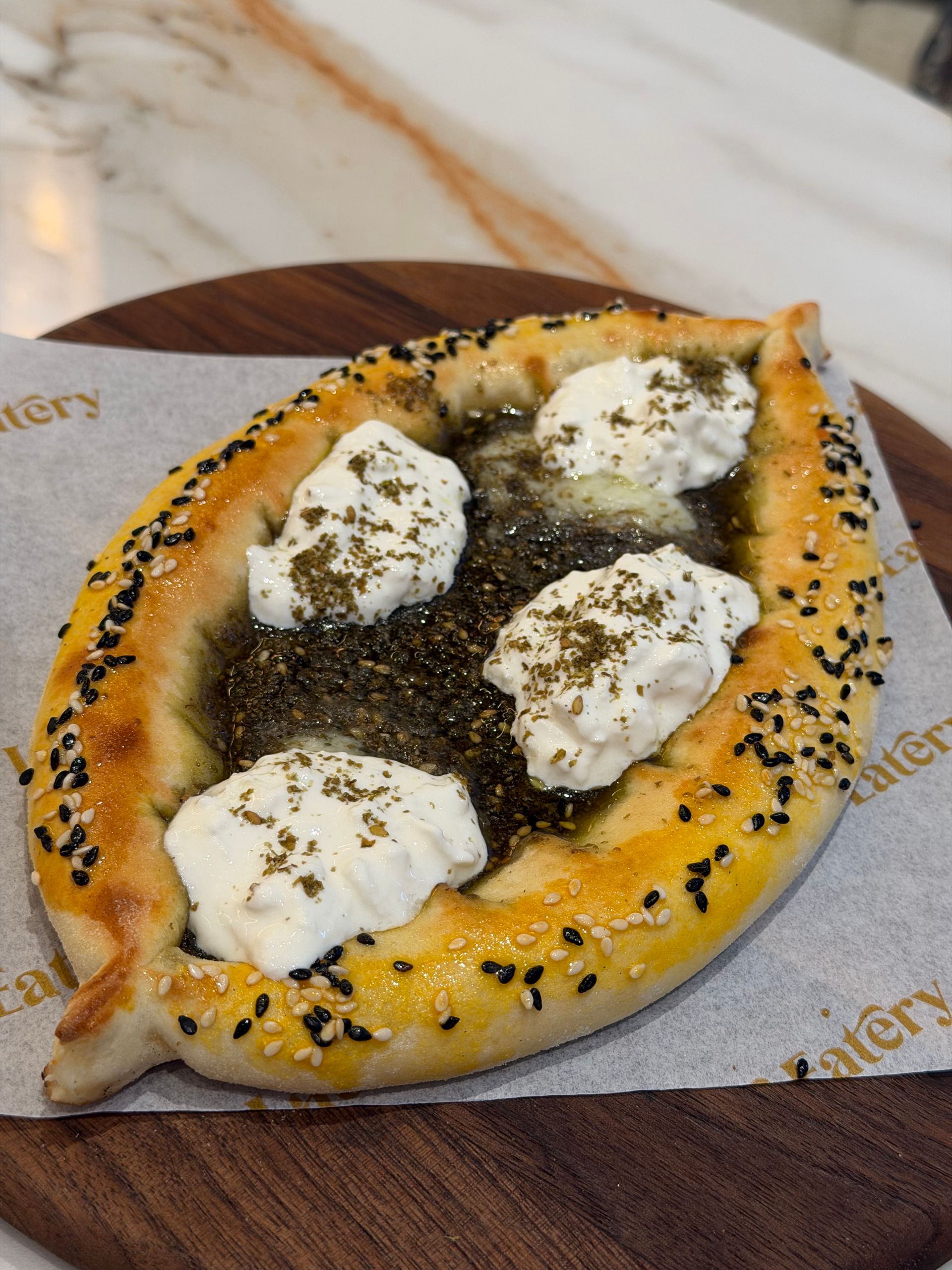 Savor this flavorful Zaatar bread topped with creamy cheese and herbs.