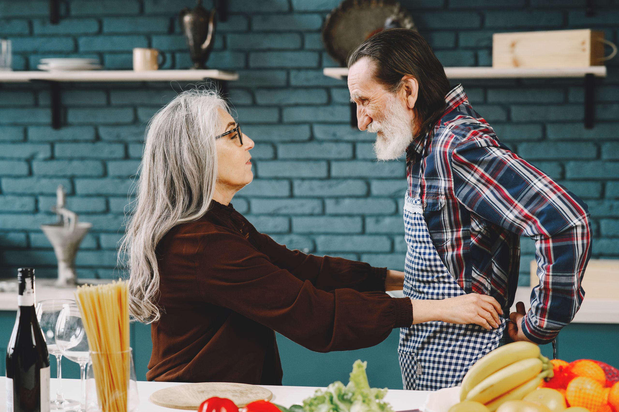 Senior couple enjoying a cooking session in a modern kitchen, showcasing love and togetherness.