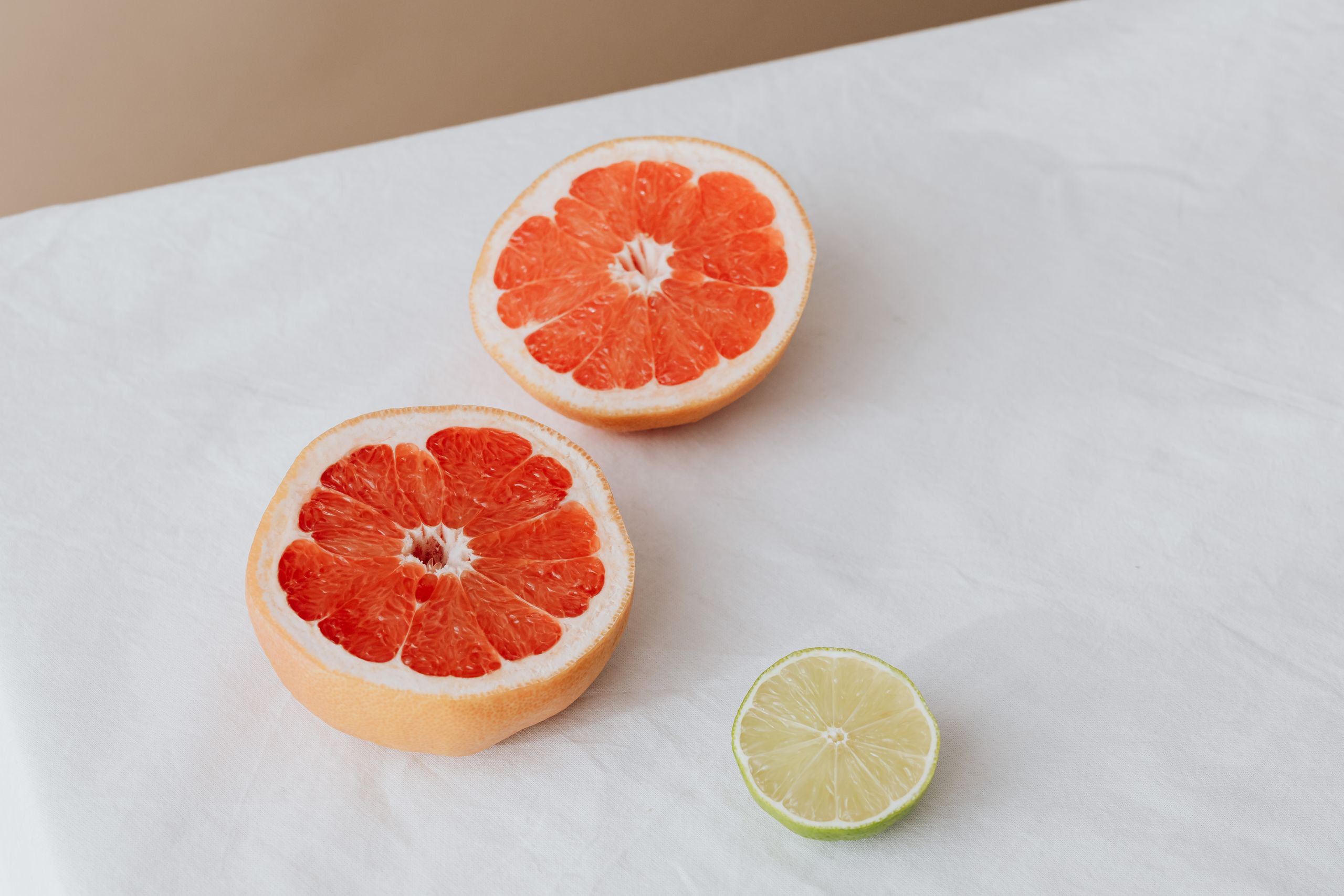 Sliced grapefruit and lime displayed on white cloth for healthy food concept.