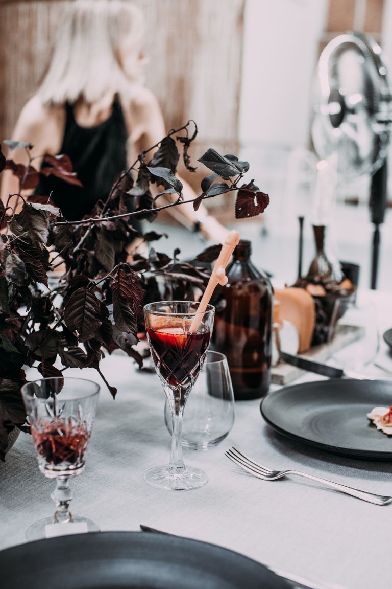 Small transparent glasses of wine and bottles with black round plates on white table in bright room on blurred background