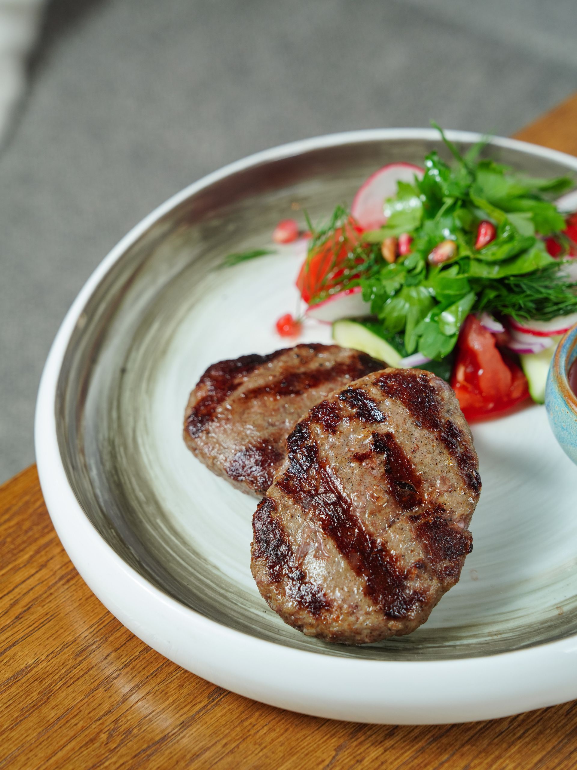 Tasty grilled beef patties served with a fresh side salad, perfect for a healthy meal.