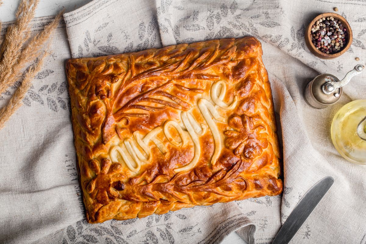 Top view of a beautifully decorated rustic pie on linen, suggesting a cozy homemade vibe.