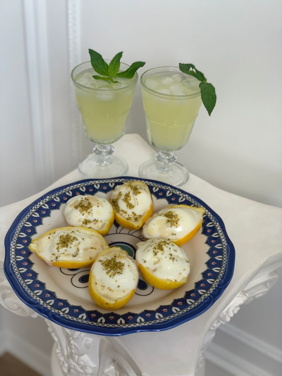 Two glasses of lemonade with mint garnish, paired with lemon zest desserts on a decorative plate.