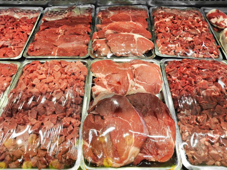 Various cuts of raw meat displayed neatly in a supermarket's refrigerated section.