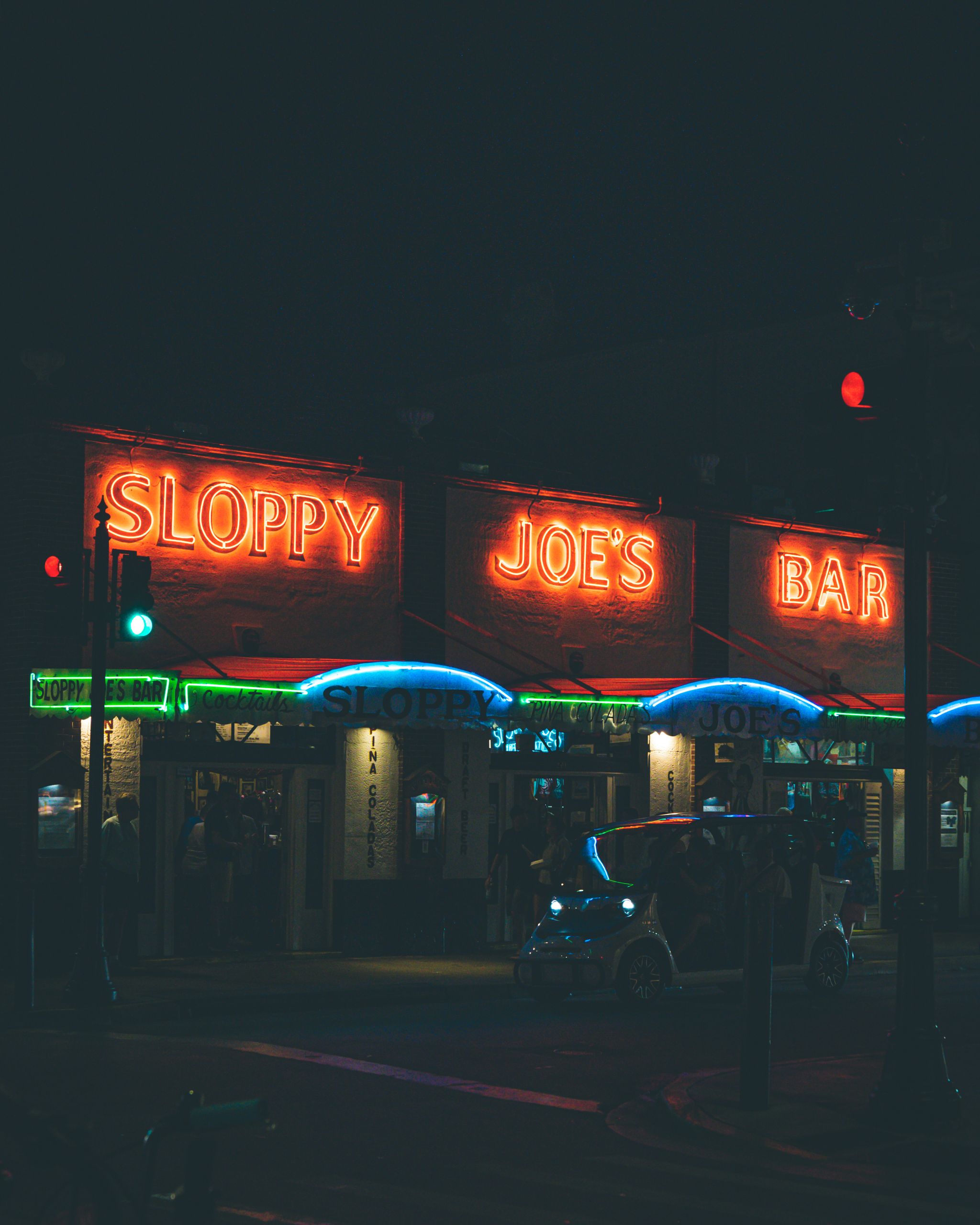 Vibrant neon lights illuminate Sloppy Joe's Bar at night in Key West, Florida, creating a lively atmosphere.