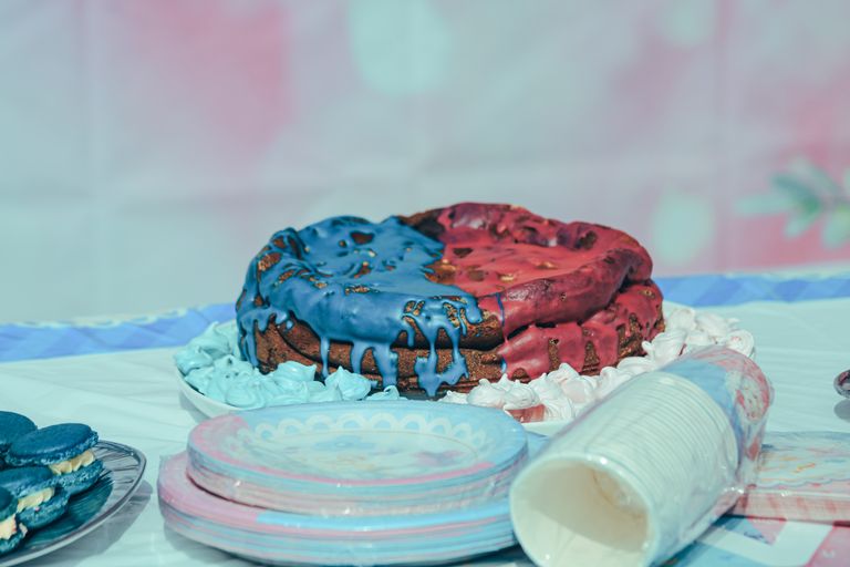 Vibrant red and blue iced cake on a table setting with plates and cups.